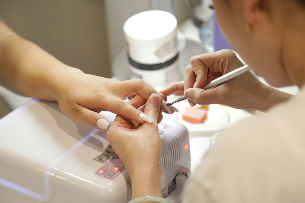 Manos de una manicurista trabajando sobre una uña