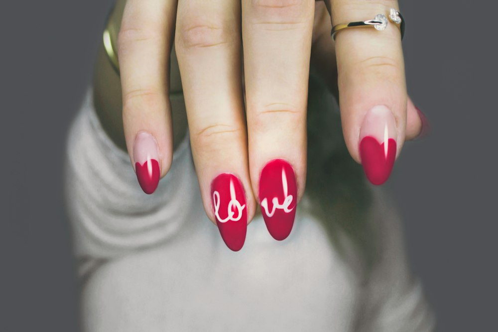 Uñas rojas con la palabra love pintada